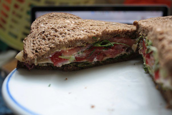 A delicious smoked salmon sandwich with lettuce, cheese, tomato and condiments.